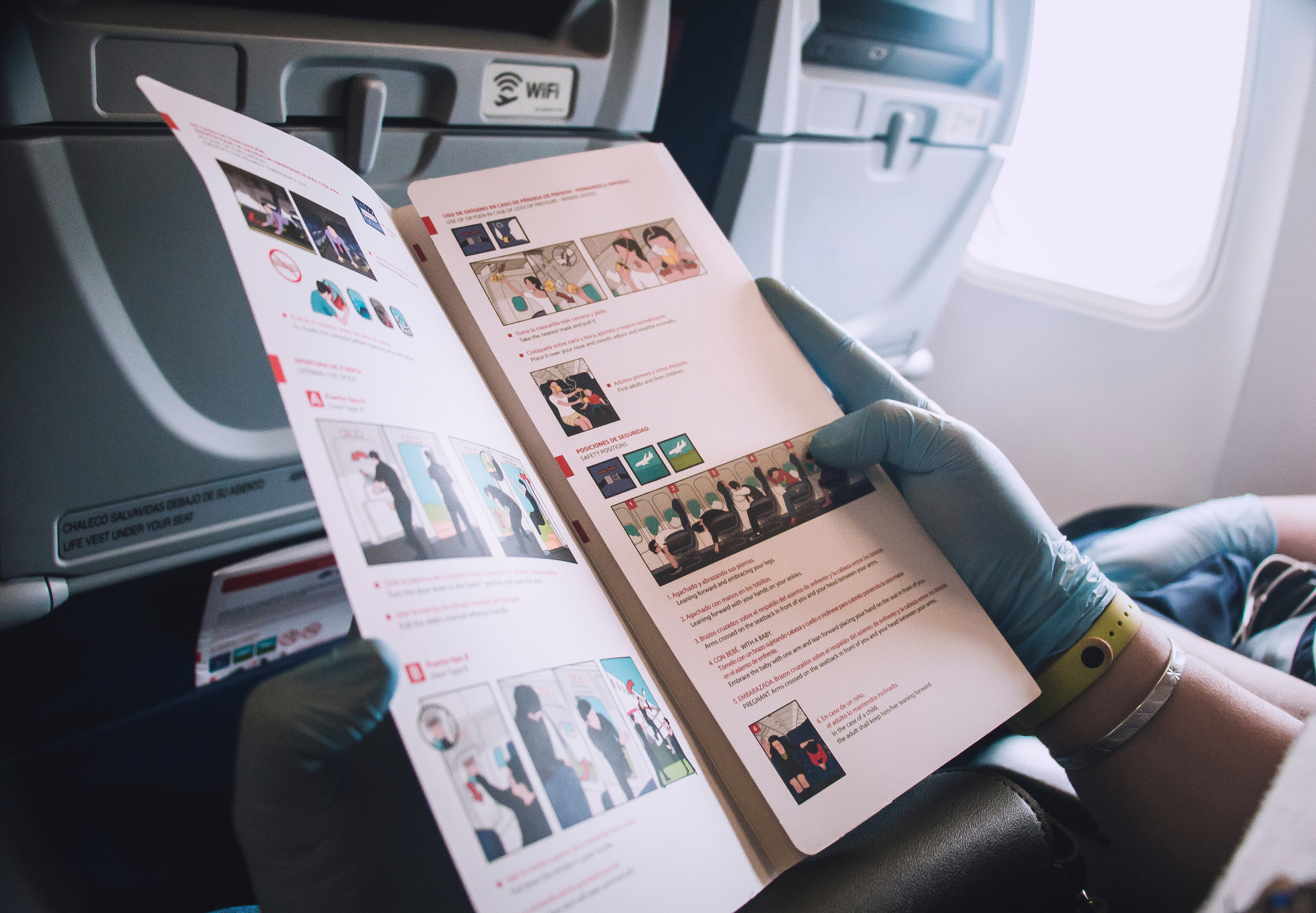 Person in Gloves Holding an Airplane Safety Brochure